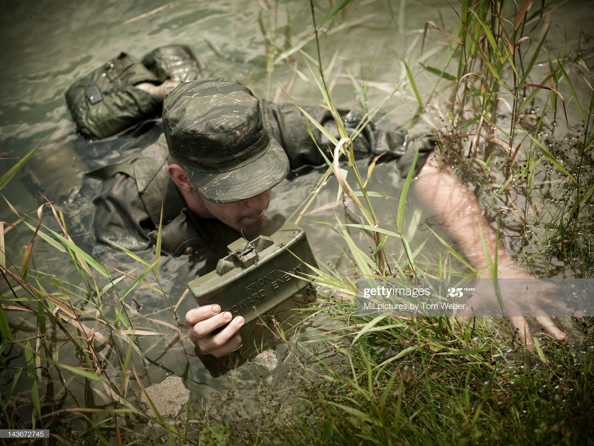 Một binh sĩ cầm quả mìn chống bộ binh ẩn nấp trong đầm lầy.