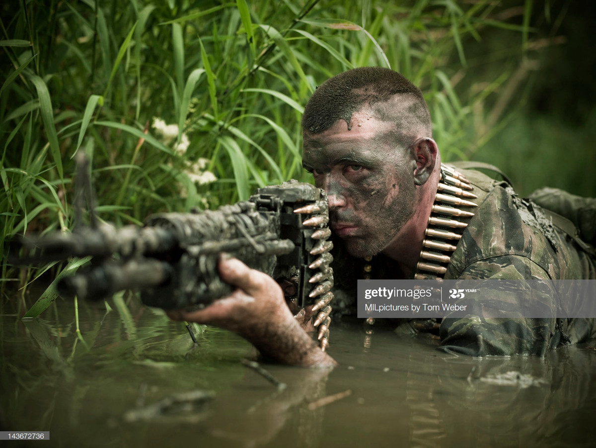 Xạ thủ Mỹ ngắm bắn bằng súng máy M60 khi nằm trên bùn lầy.