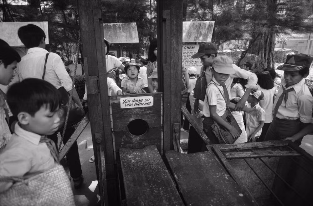 Các học sinh bên chiếc máy chém của chính quyền Ngô Đình Diệm tại "Nhà trưng bày tội ác Mỹ–ngụy" - nay là Bảo tàng Chứng tích chiến tranh.