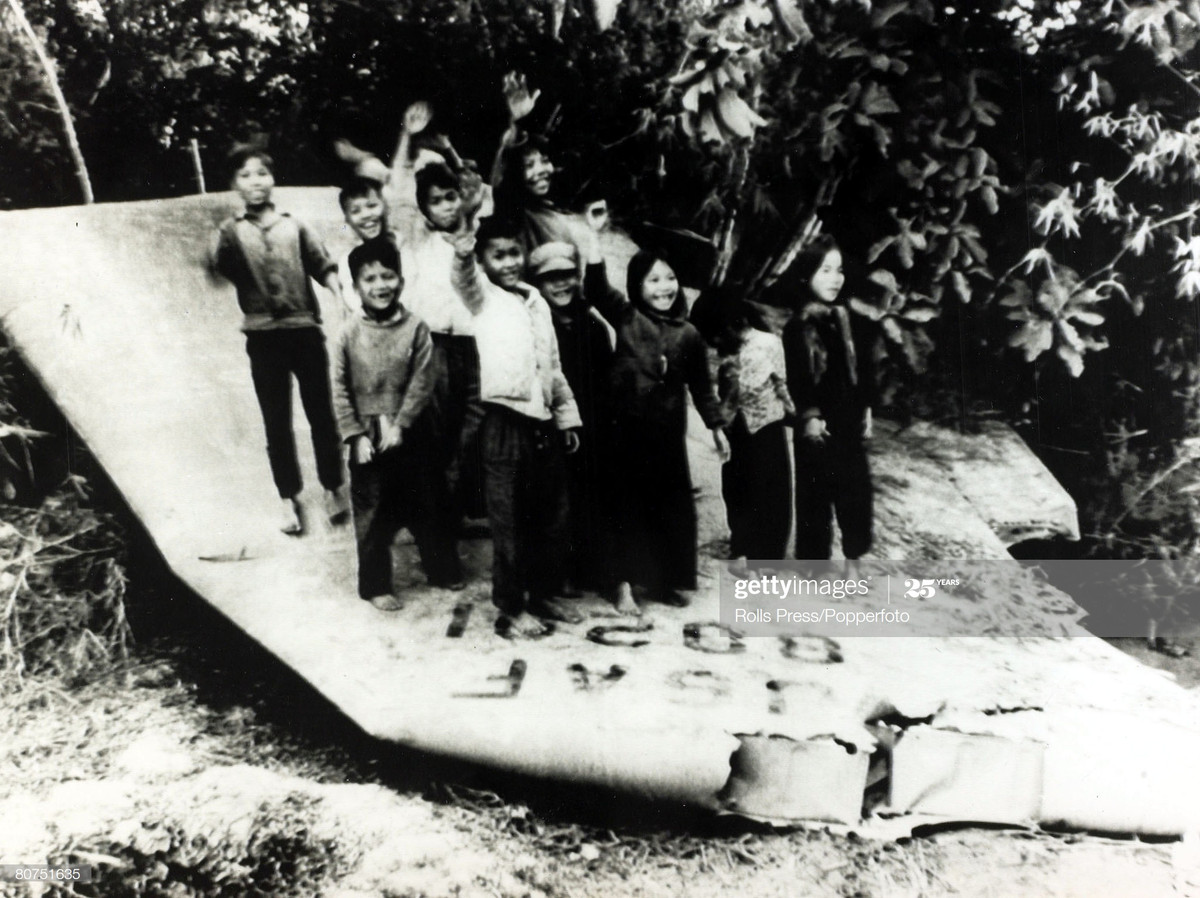 Nhóm trẻ em đứng trên xác máy bay B-52 bị bắn rơi ở miền Bắc Việt Nam, vẫy tay chào trước ống kính máy ảnh, khoảng năm 1969.