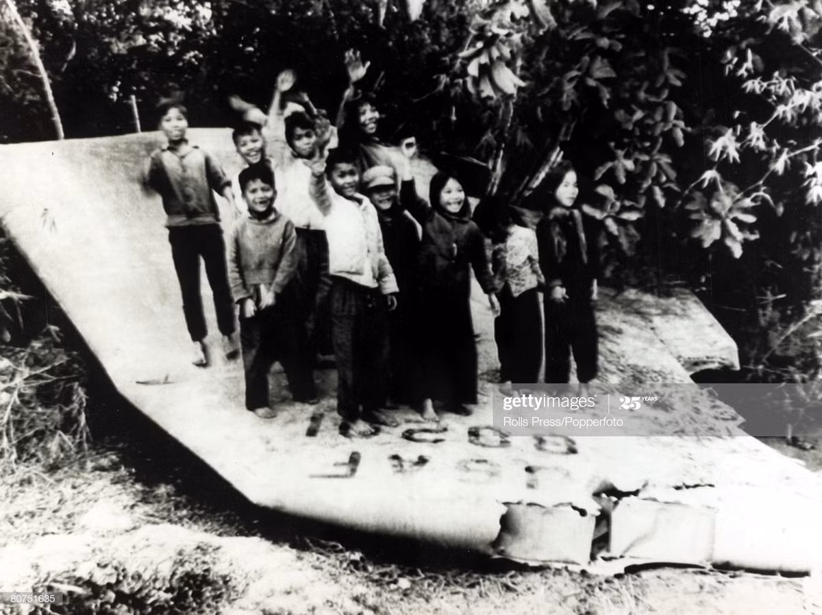 Nhóm trẻ em đứng trên xác máy bay B-52 bị bắn rơi ở miền Bắc Việt Nam, vẫy tay chào trước ống kính máy ảnh, khoảng năm 1969.