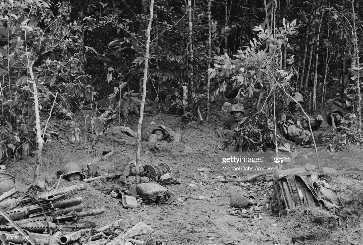 Lính Mỹ nghỉ ngơi trong những hố cá nhân được đào vội trong rừng rậm thời chiến tranh Việt Nam. Một người ngả mình nhắm mắt, trong khi những người khác nhìn quanh đẩy vẻ căng thẳng, 26/8/1966.