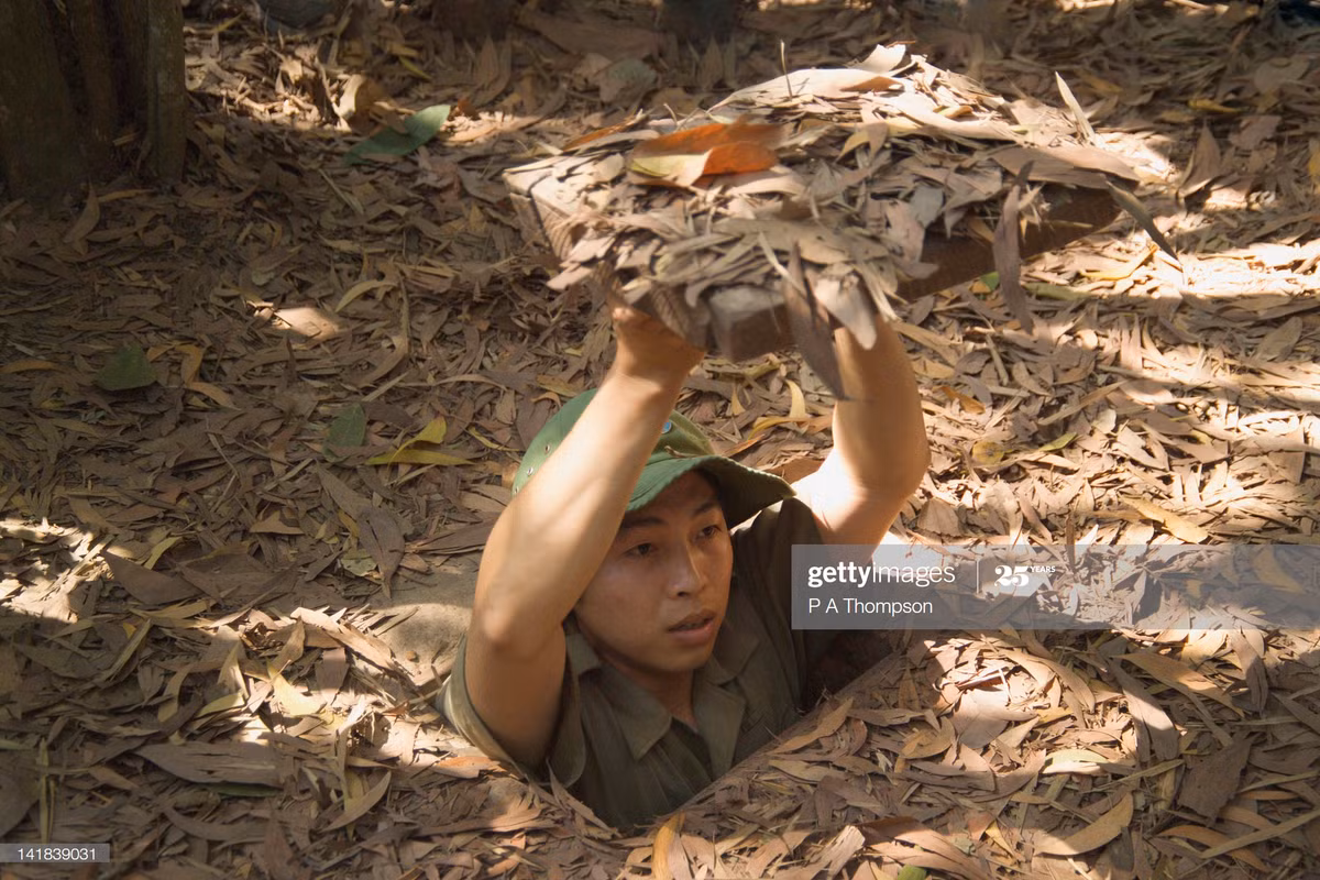 Một hướng dẫn viên mặc trang phục của chiến sĩ Giải phóng mô phỏng cách xuống địa đạo.