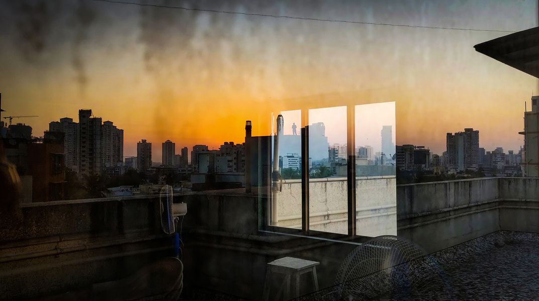 "Nhật ký phong tỏa" là bức ảnh được chụp bằng điện thoại của Mayank Soni. "Ai tin nổi thành phố này lại có thể trở thành không gian tĩnh lặng đến thế? Đại dịch chỉ cho chúng ta cách chú ý và trân trọng những gì đang có. Trong ngày đầu giãn cách, tôi thấy ai đó đứng trên sân thượng nhà bên, hình như đang suy nghĩ điều gì. Không nói gì với nhau nhưng dường như chúng tôi có chung cảm giác khi nhìn ánh hoàng hôn tỏa ra trên thành phố im lặng", Soni nói.