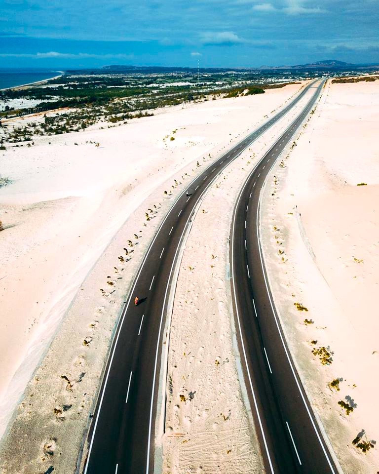 Bàu Trắng (Bình Thuận) được mệnh danh là cung đường vượt biển đẹp nhất Việt Nam. Những đoạn đường dài ngoằn ngoèo với đồi cát mênh mông là điểm khiến tín đồ xê dịch phải lòng. Mùa hè là thời điểm đẹp nhất để chinh phục cung đường "Saraha" của Bình Thuận. Đi trên cung đường này, bạn sẽ thấy làng chài Mũi Né, khu du lịch Đồi Cát Bay nổi tiếng và cả vịnh Hòn Rơm xinh đẹp. Ảnh: Chung Hiếu.