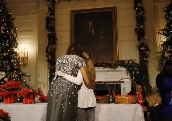 Đệ nhất phu nhân Michelle Obama âu yếm ôm con gái của một sĩ quan quân đội cấp cao của Mỹ khi cô bé giúp bà trang trí Nhà trắng để đón giáng sinh.
