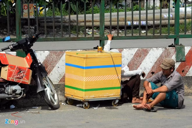 Một đôi vợ chồng ngồi chờ khách ngay giữa đường cùng với đồ nghề buôn bán.