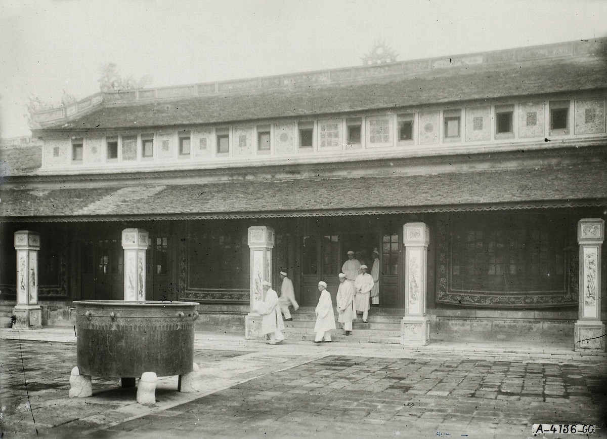 Các quan thượng thư bước ra từ một khu nhà thuộc Điện Càn Thành (nay không còn). Các vị đi đầu là Tôn Thất Hân, Nguyễn Hữu Bài và Hồ Đắc Trung.