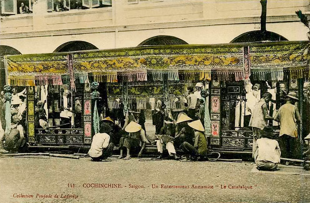 Các phu nhà đòn ngồi bên xe tang trong lúc chờ quan tài được khiêng ra xe.