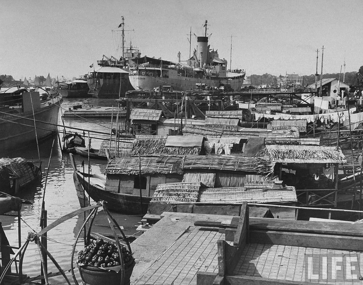 Thuyền bè thô sơ của cư dân địa phương chen chúc cạnh các tàu chở hàng khổng lồ của Pháp trên sông Sài Gòn.