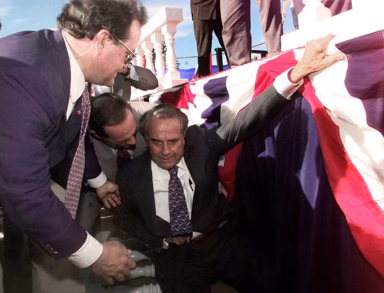 Ứng cử viên tổng thống đảng Cộng hòa Bob Dole được các nhân viên mật vụ đỡ dậy sau khi ông ngã khỏi sân khấu trong một cuộc vận động tranh cử ở Chico, bang California, ngày 18/9/1996.
