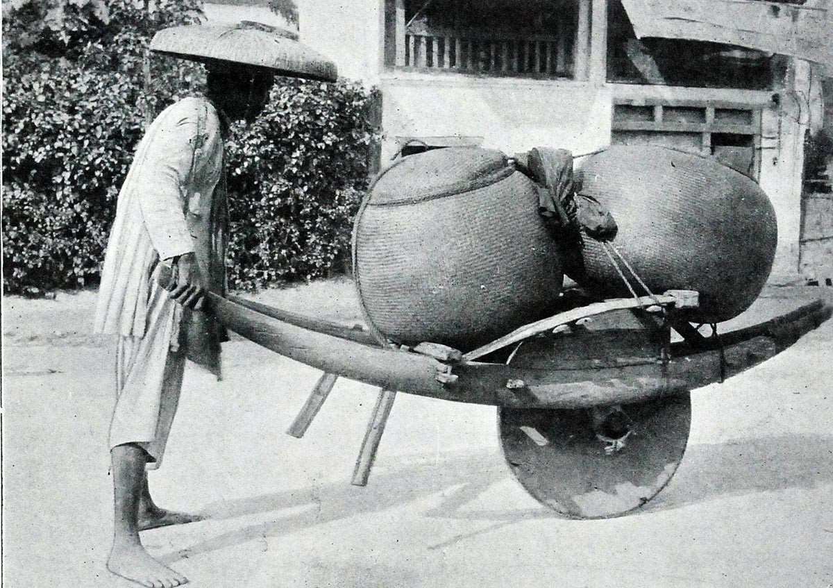 Một cu-li xứ Bắc Kỳ vận chuyển gạo bằng xe cút kít.