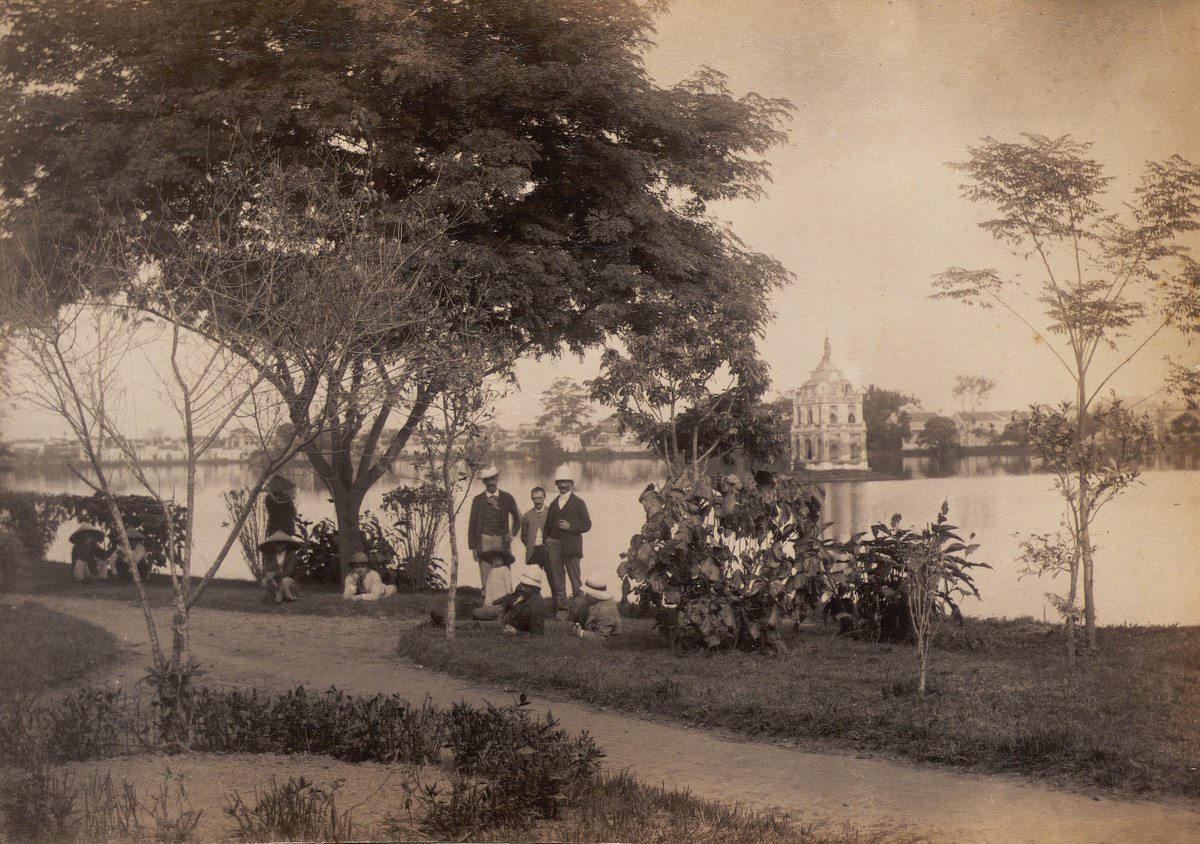 Trên bờ hồ Hoàn Kiếm. Phía xa là Tháp Rùa với tượng Thần Tự do trên đỉnh tháp.