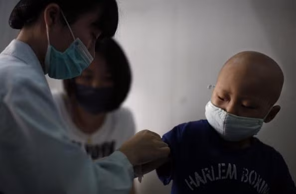 Niuniu đang được y tá lấy máu xét nghiệm bên cạnh mẹ.