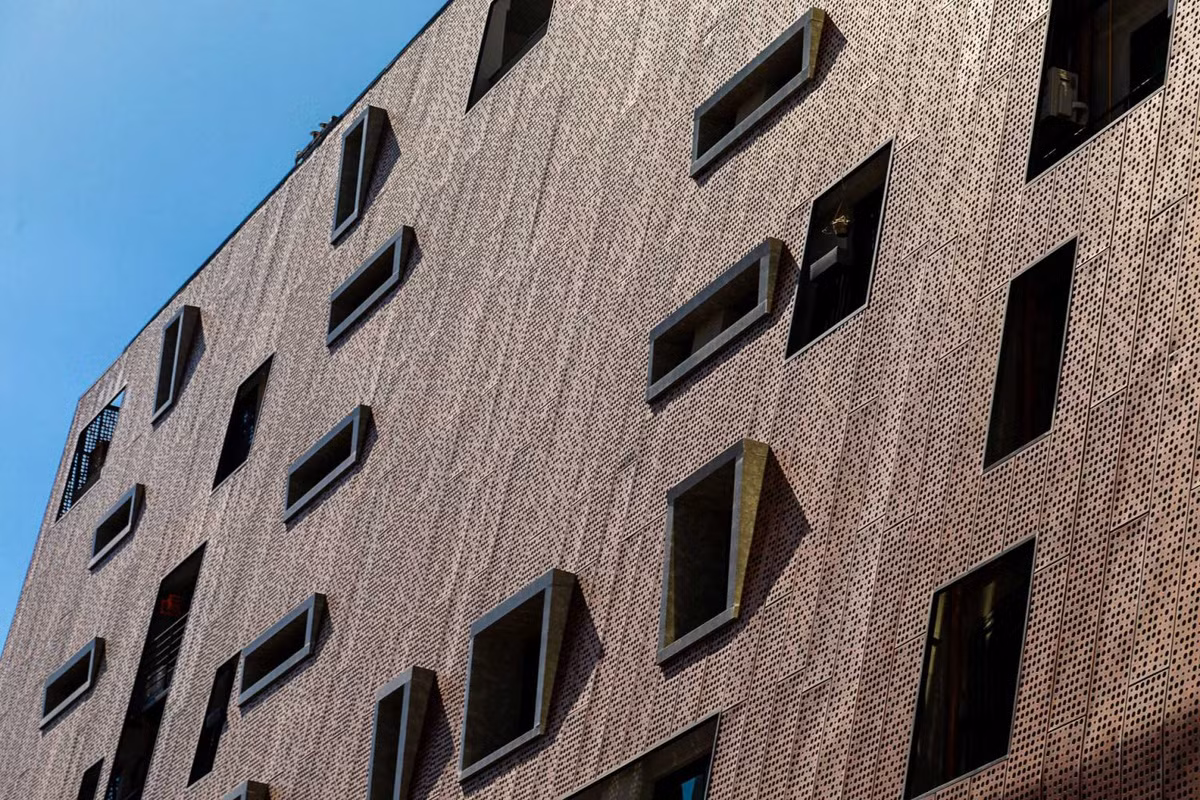 Lớp kim loại này che mặt tiền toà nhà khỏi ánh nắng trực tiếp, cung cấp đủ ánh sáng tự nhiên cho các căn hộ, cho phép người trong nhà quan sát được khu vực xung quanh nhưng vẫn đảm bảo sự riêng tư cho chủ nhân.