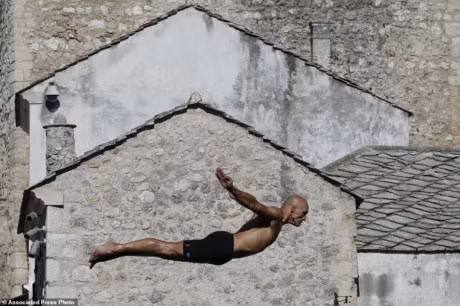 Một vận động viên thực hiện phần thi của mình với nền là những ngôi nhà cổ ở phía xa.