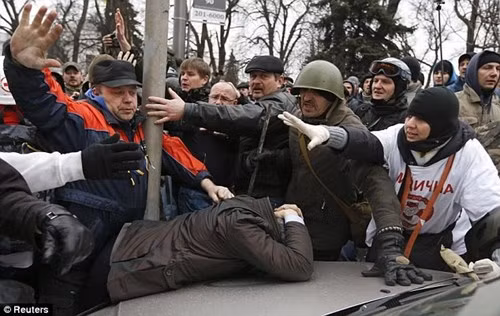 Những người biểu tình chống chính phủ đánh đạp một người ủng hộ Tổng thống Yanukovych.