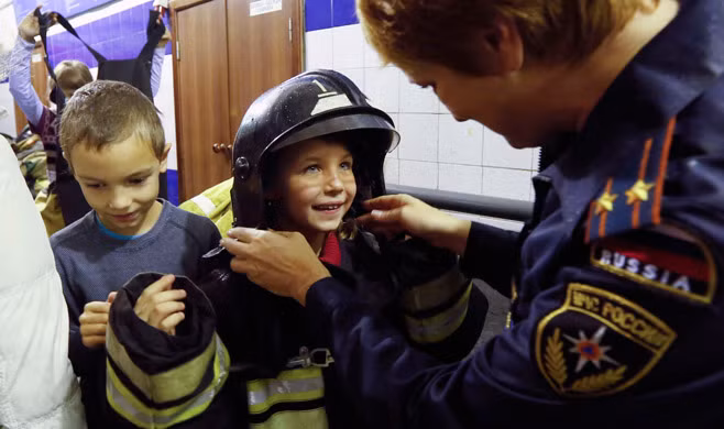 Những trẻ em tị nạn người Ukraine vui đùa với một anh lính cứu hỏa Nga ở trạm Krasnoyarsk.