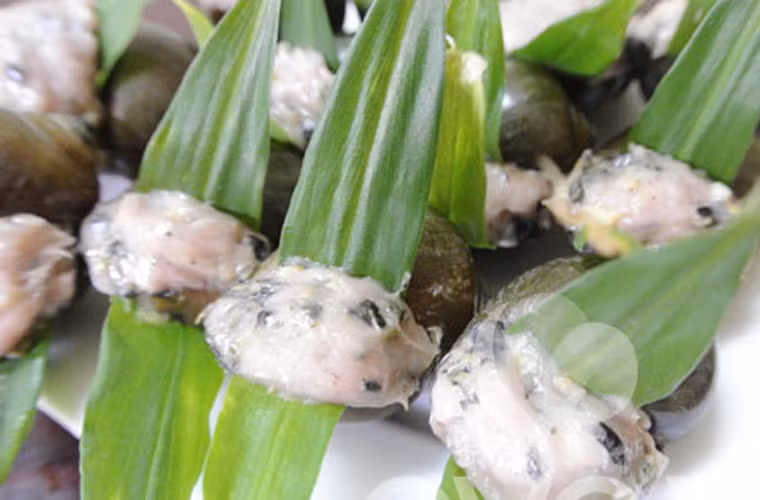 Ốc hấp lá gừng. Để có được những miếng ốc hấp lá gừng nhỏ nhắn, các bà nội trợ cần băm nhỏ thịt ốc rồi trộn chung với giò sống, bọc lá gừng rồi hấp đến khi chín tới là có thể ăn được.