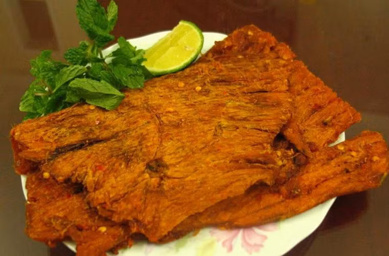  Khô bò nướng. Thịt bò khô nướng vừa lửa trở nên sậm hơn, gia vị bám chắc và ngấm vào từng thớ thịt. Chính vị cay cay, ngọt ngọt khiến khô bò nướng trở thành món nhắm khó cưỡng trong những ngày trời đổ mưa.