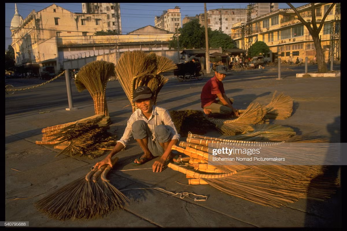 Những người bán chổi đót bày hàng ở Công trường Mê Linh. Góc trên bên trái là chóp mái của khách sạn Grand.