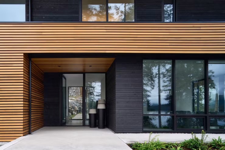 Một bảng màu vật liệu ngoại thất tối thiểu bao gồm vách ngăn bằng gỗ tuyết tùng và vải phủ bằng gỗ tuyết tùng mang lại sự ấm áp và kết cấu độc đáo, đồng thời liên kết tòa nhà với khu rừng tuyết tùng xung quanh.