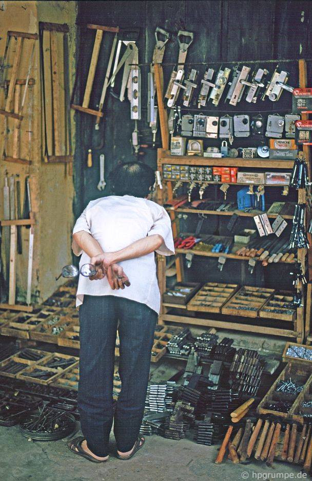 Một khách hàng ngắm nghía các loại khóa, bản lề... trên phố Thuốc Bắc.