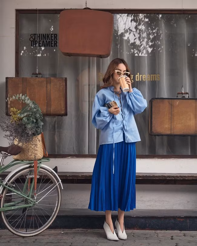 Khéo mix chân váy xếp ly với mẫu áo tay bồng cùng tông màu xanh da trời, Yến Trang có được tổng thể trang phục rất hài hòa, ưng mắt.