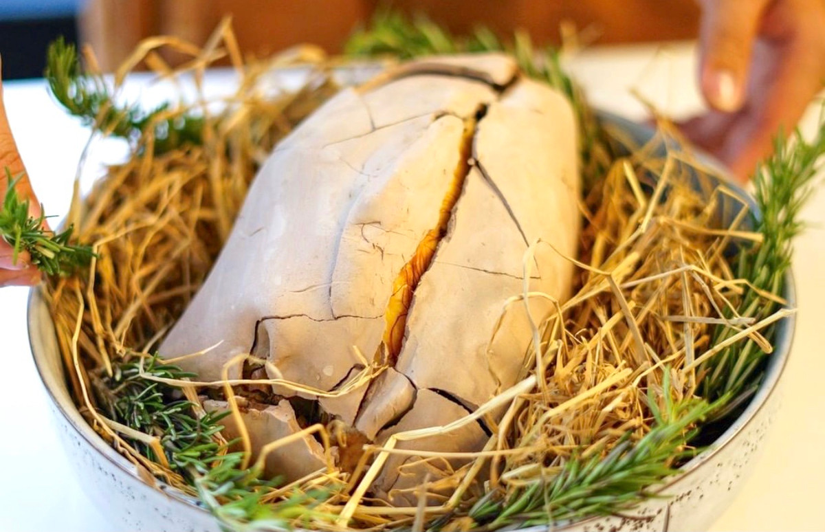 Gà nướng đất sét (hay còn có tên "gà ăn mày") là món ăn có nguồn gốc từ Trung Quốc. Đặc sản này cũng quen thuộc với người miền Tây. Gà được sơ chế kỹ, tẩm ướp gia vị. Nguyên liệu quan trọng tạo mùi thơm là lá chanh và sả băm nhét vào bụng gà. Khi đã ngấm vị, người làm tiếp tục lấy lá sen, lá chuối bọc quanh rồi đắp đất sét lên cho thật kín, cuối cùng đem nướng từ từ trên lửa nhỏ. Ảnh: Sapconceptstore.