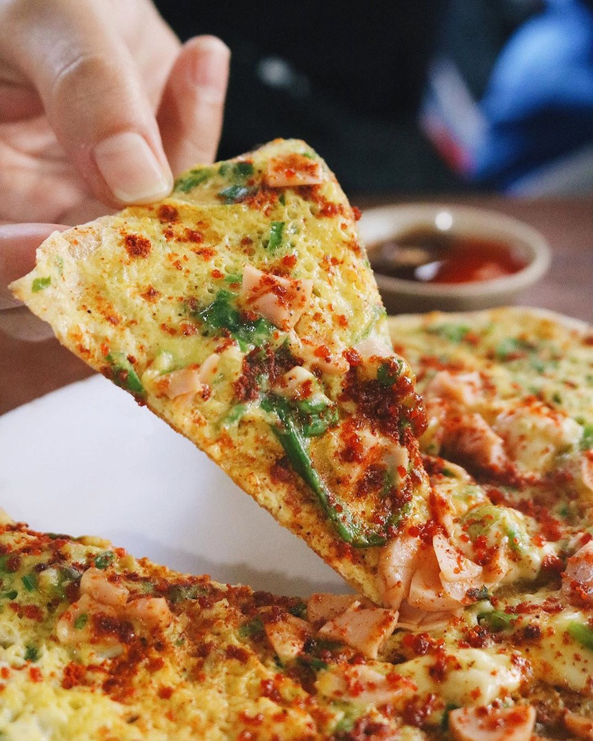 Bánh tráng nướng là món ăn vặt đặc trưng của thành phố sương mù. Món ăn nổi tiếng với du khách trong và ngoài nước với tên gọi "pizza" Việt Nam. Bánh tráng được nướng trên bếp than, kết hợp với các topping phong phú như ruốc, phô mai, bò khô, hành phi... Vị đậm đà, béo thơm của các loại nhân hòa quyện với nhau tạo nên chiếc "pizza" phiên bản Việt. Ảnh: Pha.foodie.