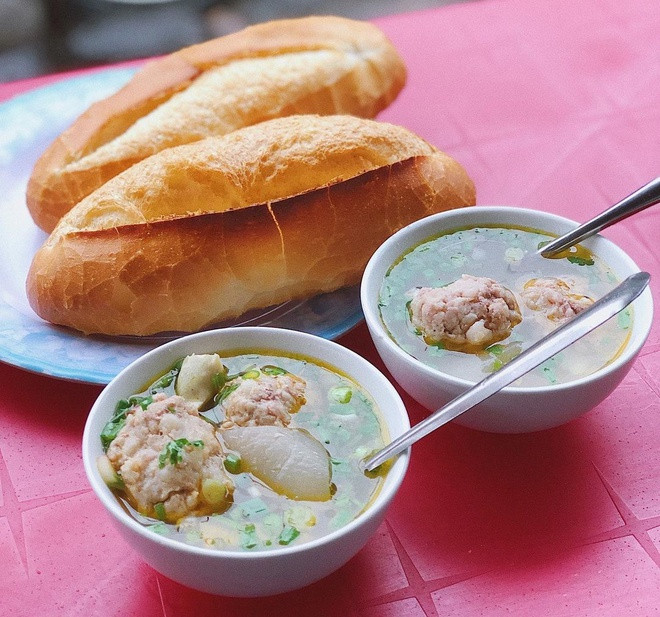 br/> Đến Đà Lạt, du khách có thể chọn bánh mì xíu mại chén để thưởng thức cho bữa sáng. Những ổ bánh mì nóng giòn được để riêng. Phục vụ kèm là chén xíu mại nhiều nước dùng ấm nóng, vị hơi nhạt, có thể cay nếu thêm ớt, ngoài ra còn có chả gói lá, da heo luộc, hành lá xắt nhuyễn. Khi ăn, thực khách sẽ xé nhỏ bánh mì, chấm nước dùng. Ảnh: Ruahaman.