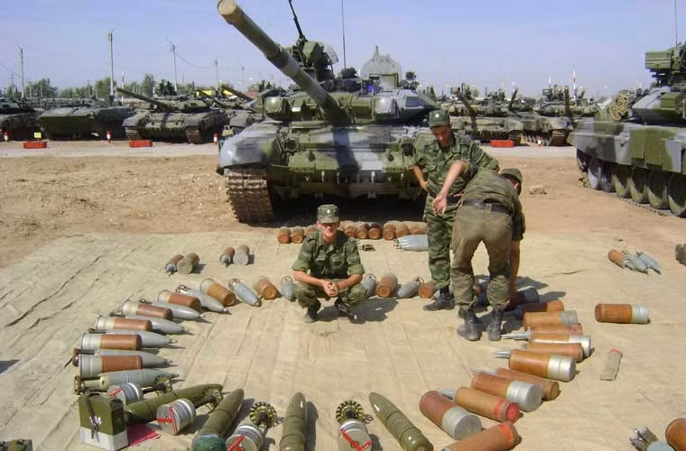 Ba chiến sĩ lái tăng Nga đứng trong vòng tròn các loại đạn pháo của xe tăng chiến đấu chủ lực T-90A. Pháo 2A46 125mm trên T-90 có thể bắn đạn xuyên giáp APFSDS, đạn nổ chống tăng HEAT, đạn nổ phá mảnh HE-FRAG, tên lửa chống tăng 9M119 Refleks.