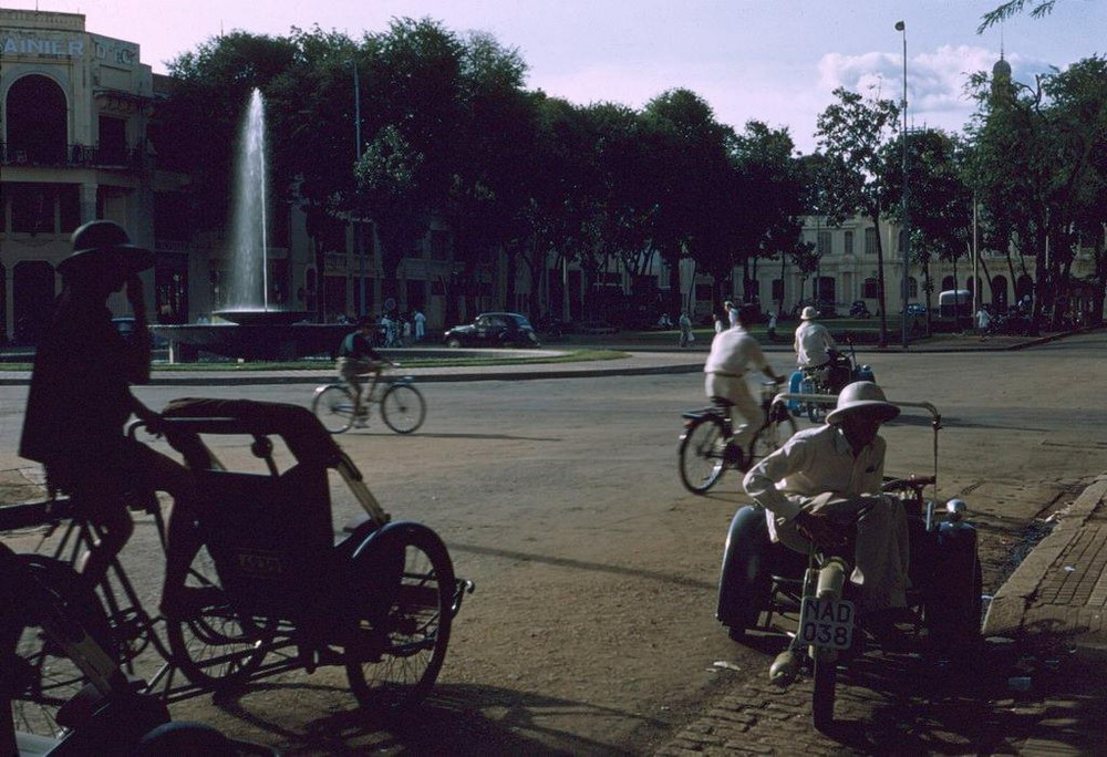 Người lái xích lô máy chờ khách ở ngã tư Charner - Bonard (Nguyễn Huệ - Lê Lợi), phía xa là Dinh Xã Tây (UBND TP HCM), Sài Gòn năm 1954.