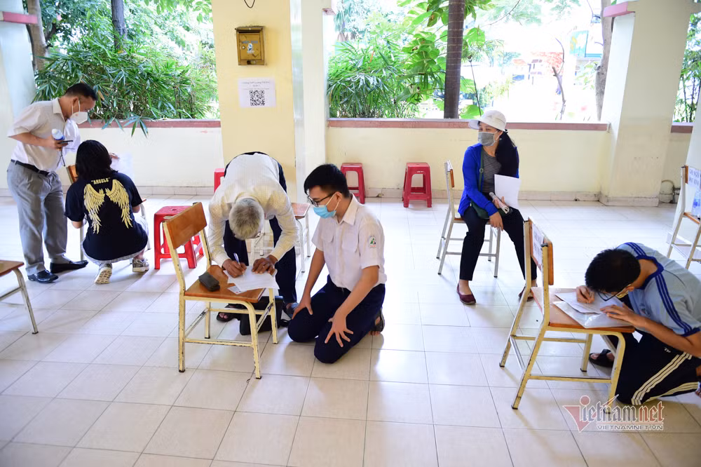 Phụ huynh cùng con ghi thông tin để được tiêm. Ông Nguyễn Văn Hiếu, phụ huynh em Nguyễn Đức Tiến, cho biết, ông dắt con đi tiêm không lo lắng mà còn mong được tiêm sớm để trẻ được đi học.