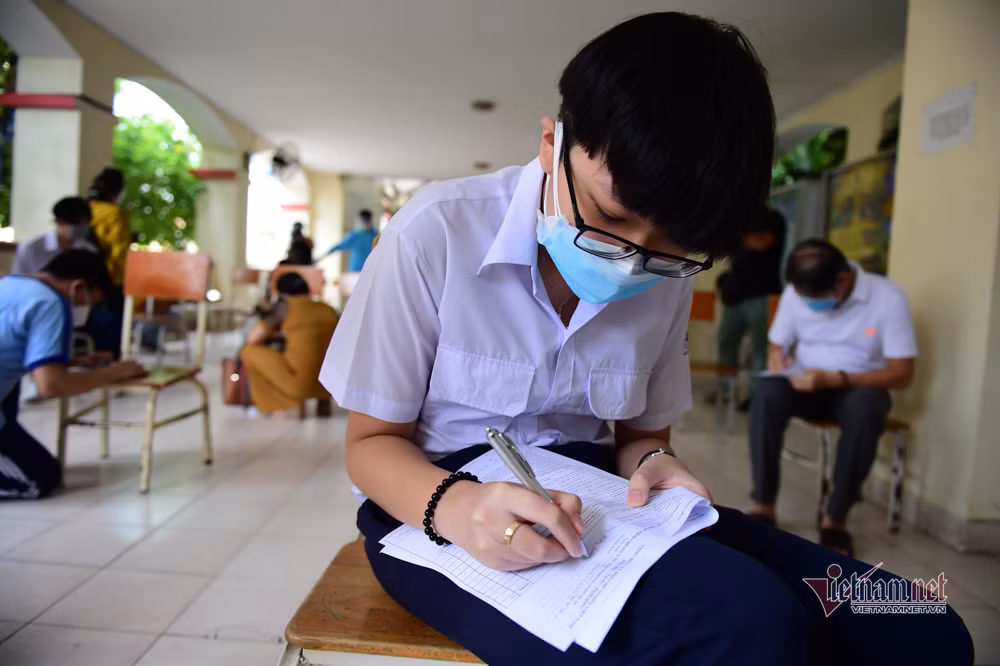 Em Phạm Phú Lộc ghi thông tin trước khi tiêm. Em cho biết: "Mọi người ai cũng tiêm nên em không thấy lo lắng gì".