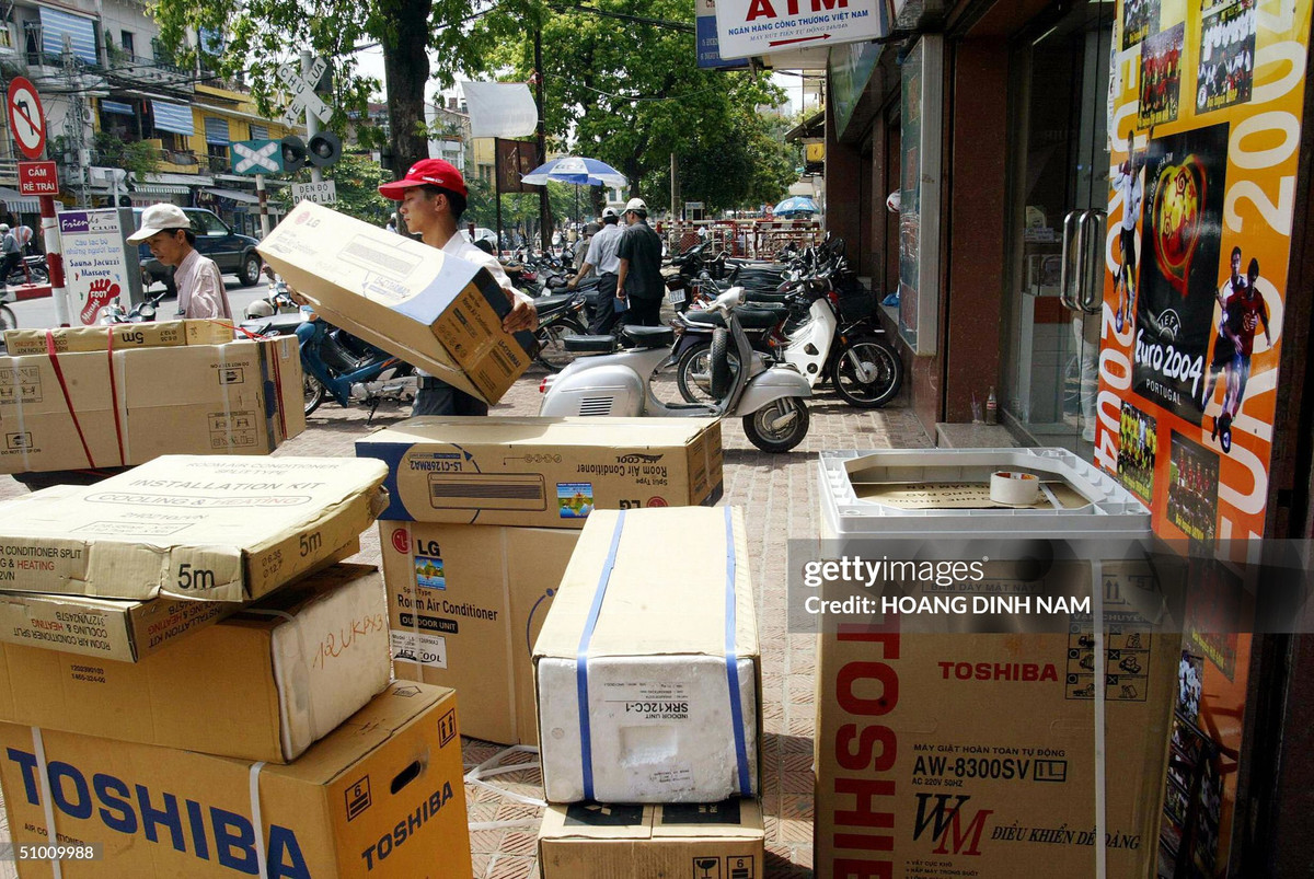 Nhân viên bốc dỡ các thùng máy điều hòa tại cửa hàng điện máy số 5 phố Điện Biên Phủ, 30/6/2004.