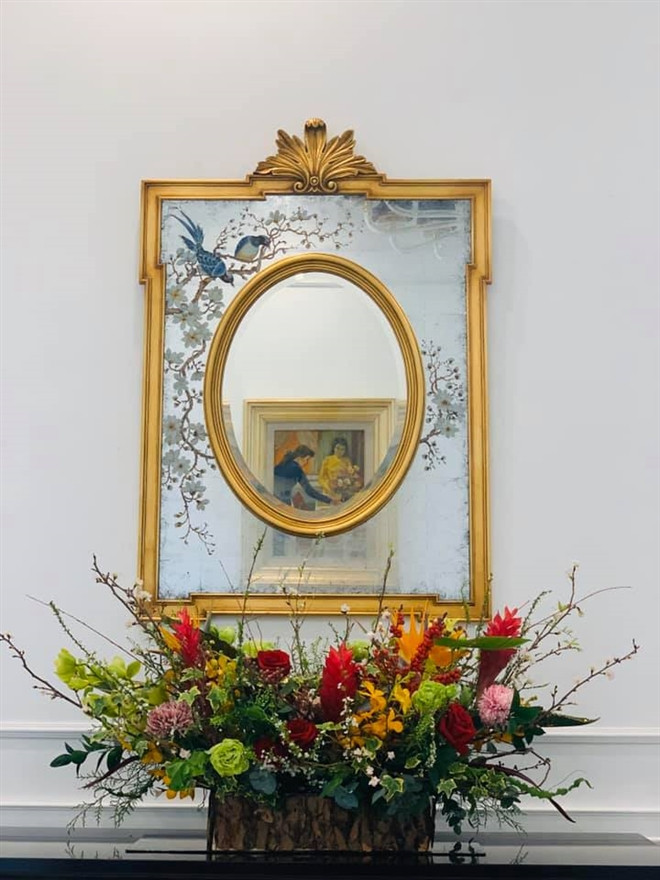 Một lẵng hoa đặt trước tấm gương theo phong cách cổ điển châu Âu.