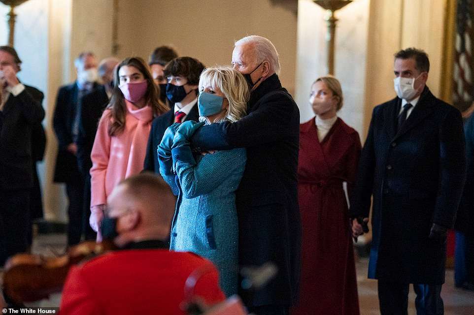 Tổng thống Joe Biden ôm từ đằng sau Đệ nhất phu nhân Jill Biden khi ban nhạc Thủy quân lục chiến biểu diễn chào đón họ đến Nhà Trắng vào ngày nhậm chức.