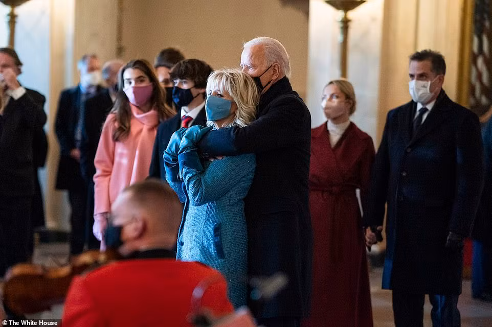 Tổng thống Joe Biden ôm từ đằng sau Đệ nhất phu nhân Jill Biden khi ban nhạc Thủy quân lục chiến biểu diễn chào đón họ đến Nhà Trắng vào ngày nhậm chức.