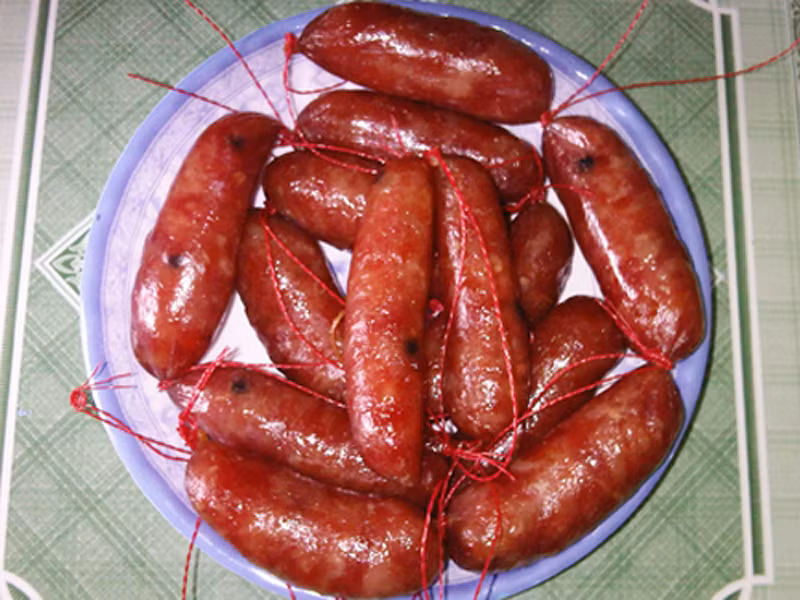 Khi ăn, bánh phở được dàn đều ra đĩa. Thịt lợn, lạp xưởng rán cháy cạnh, xúc xích, hành khô, lạc giã, rau thơm được phủ lên trên.