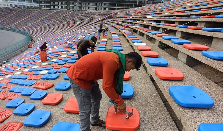 ...Công nhân dùng búa để bắt đinh gắn chặt ghế vào bê tông. Ảnh: CTP