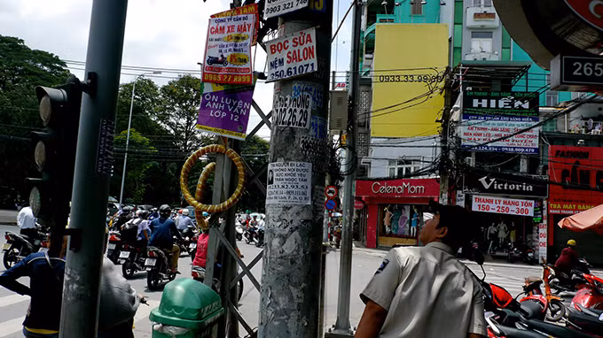 Cột điện thép, cột ximăng ở ngã tư Hai Bà Trưng – Võ Thị Sáu, P.8, Q.3 đều bị treo, dán quảng cáo.