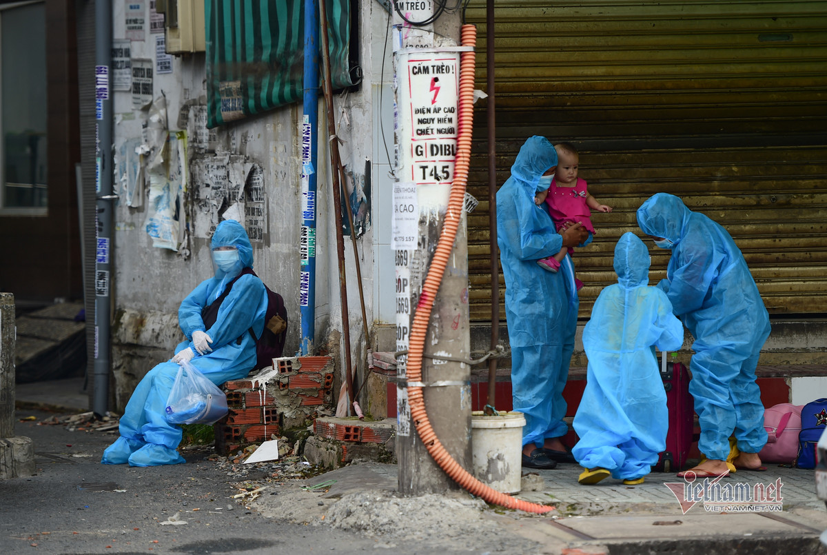 Gia đình ngồi bên đường chờ giảm bớt người mới sang làm thủ tục.