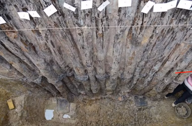 Chi tiết hàng cọc gỗ và dây buộc liên kết bao quanh kiến trúc trung tâm.