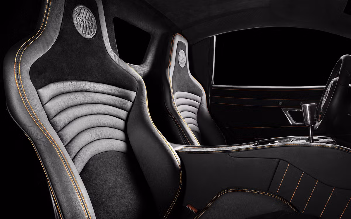 Ghế ngồi bọc da xám, đệm nhung ở vị trí lưng và cổ. Viền ghế màu da cam nổi bật, hợp tông với màu xe.