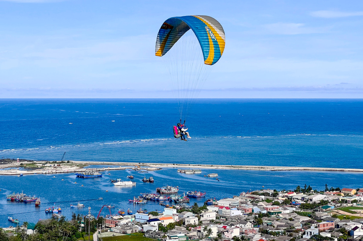 Các vận động viên biểu diễn dù lượn gần khu vực Vũng neo đậu tàu thuyền Lý Sơn.