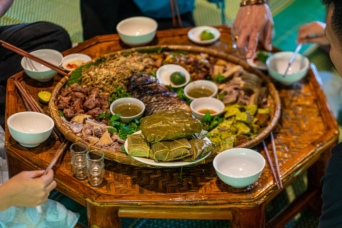 Buổi trưa, đoàn dùng cơm ngay tại nhà sàn. Mâm cỗ Tày tiếp đãi khách bày trên chiếc mẹt tre mộc mạc, mang đặc trưng rừng núi với cá bỗng sông Gâm, trứng tráng rau hôi, da trâu xào măng chua, rau dớn...