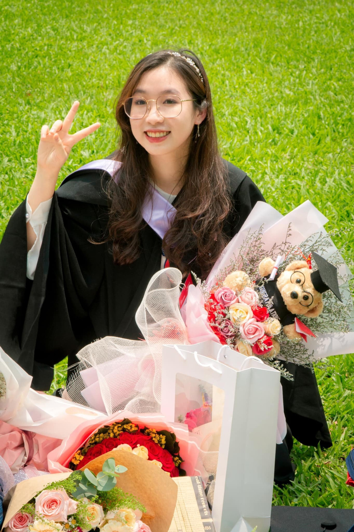Nữ sinh Dương Ngọc Phương, tốt nghiệp ngành Quản lý Kinh doanh, tạo dáng chụp hình bên hoa và quà từ người thân, bạn bè gửi tặng.