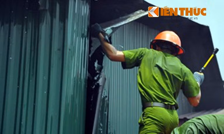 Chiến sĩ công an liên tục phá các tấm tôn bao quanh kho cồn để chữa cháy.