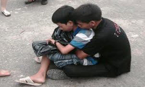 Cường trong vòng tay của người thân. Trên tay cháu cầm di ảnh mẹ để trong túi nylon.